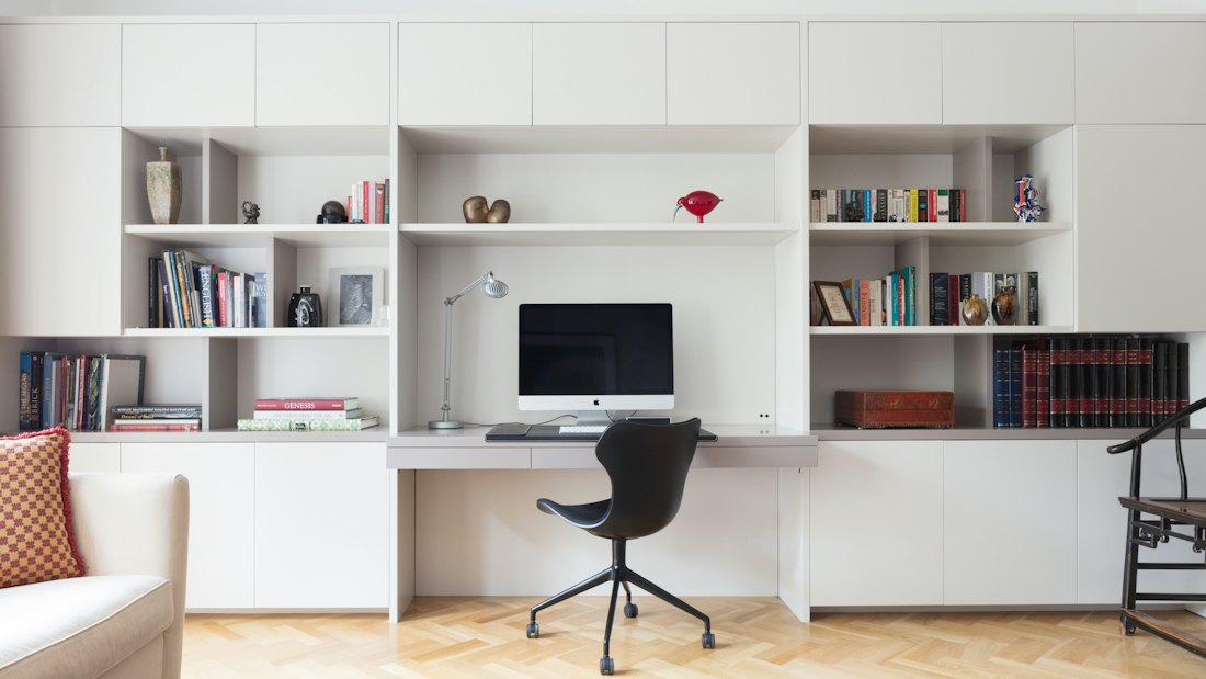 Bureau intégré sur mesure : mur de rangement blanc avec bibliothèques, plan de travail et poste de travail.