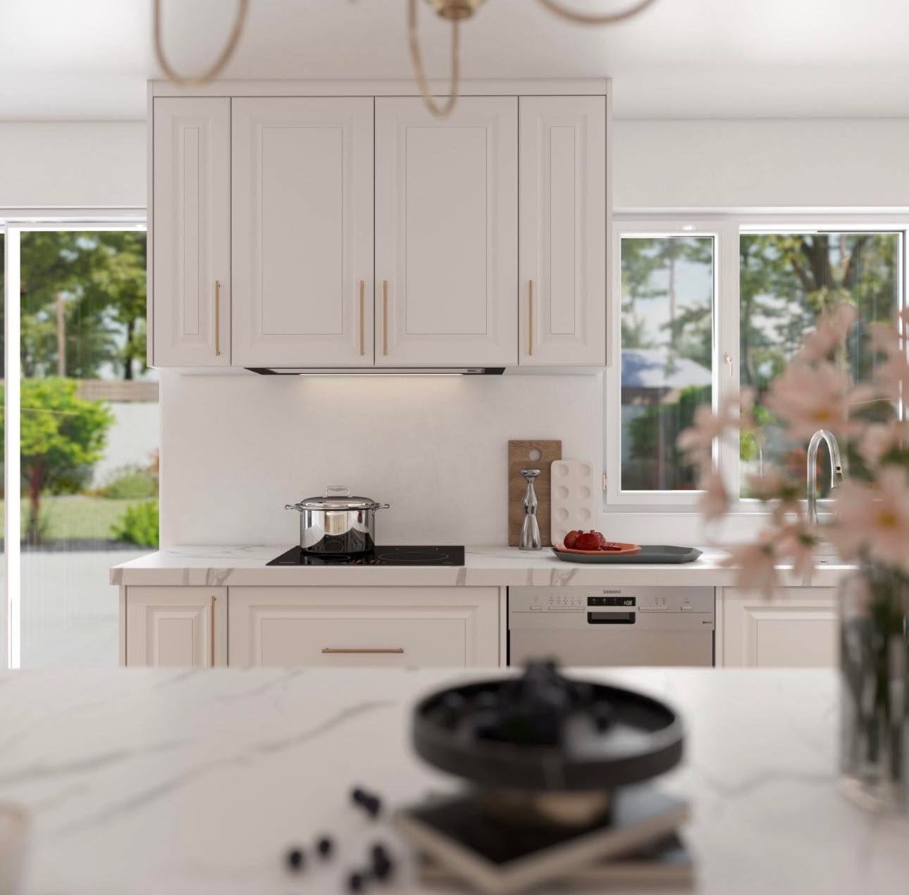 Cuisine sur mesure Ebanista à façades crème de style shaker, hotte intégrée dans les armoires hautes, plaque à induction et comptoir de quartz veiné.